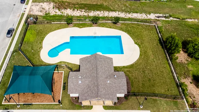 an aerial view of a swimming pool with outdoor space and seating area
