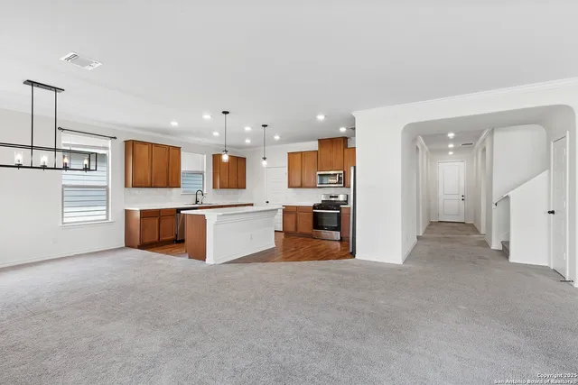 a large kitchen with stainless steel appliances kitchen island a large counter top and a refrigerator
