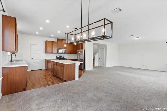 a kitchen with stainless steel appliances kitchen island a refrigerator sink and cabinets