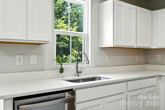 a kitchen with granite countertop a sink a counter space appliances and cabinets