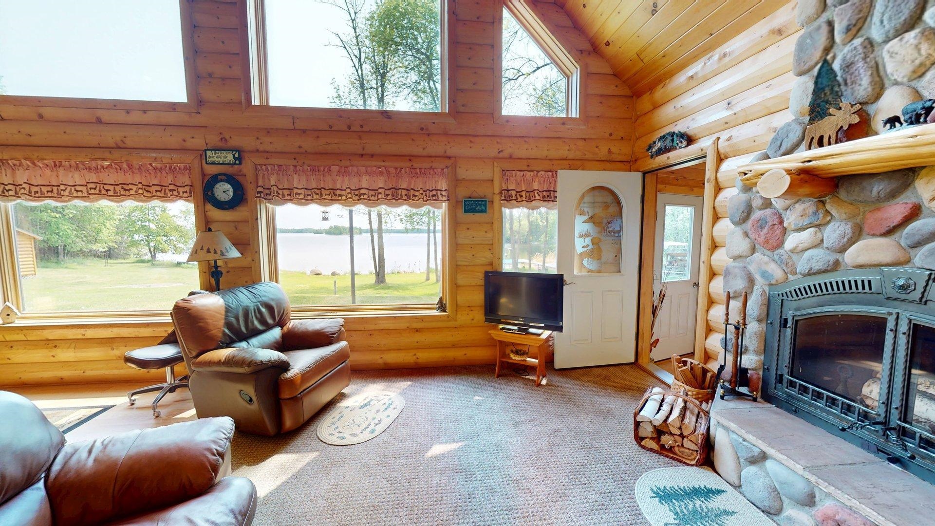 10898 Bessette Road Orr, MN 55771 - Photo 14 of 49 Living room with high vaulted ceiling, log walls, wood ceiling, a fireplace, and carpet flooring