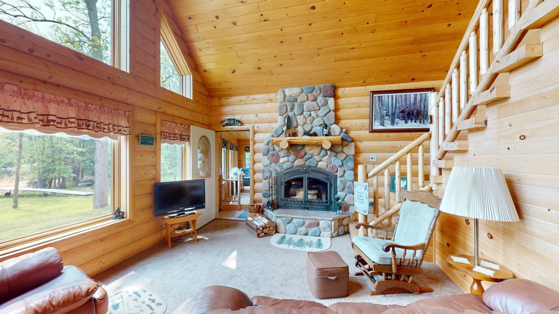 10898 Bessette Road Orr, MN 55771 - Photo 16 of 49 Living room featuring log walls, high vaulted ceiling, carpet flooring, stairs, and wood ceiling