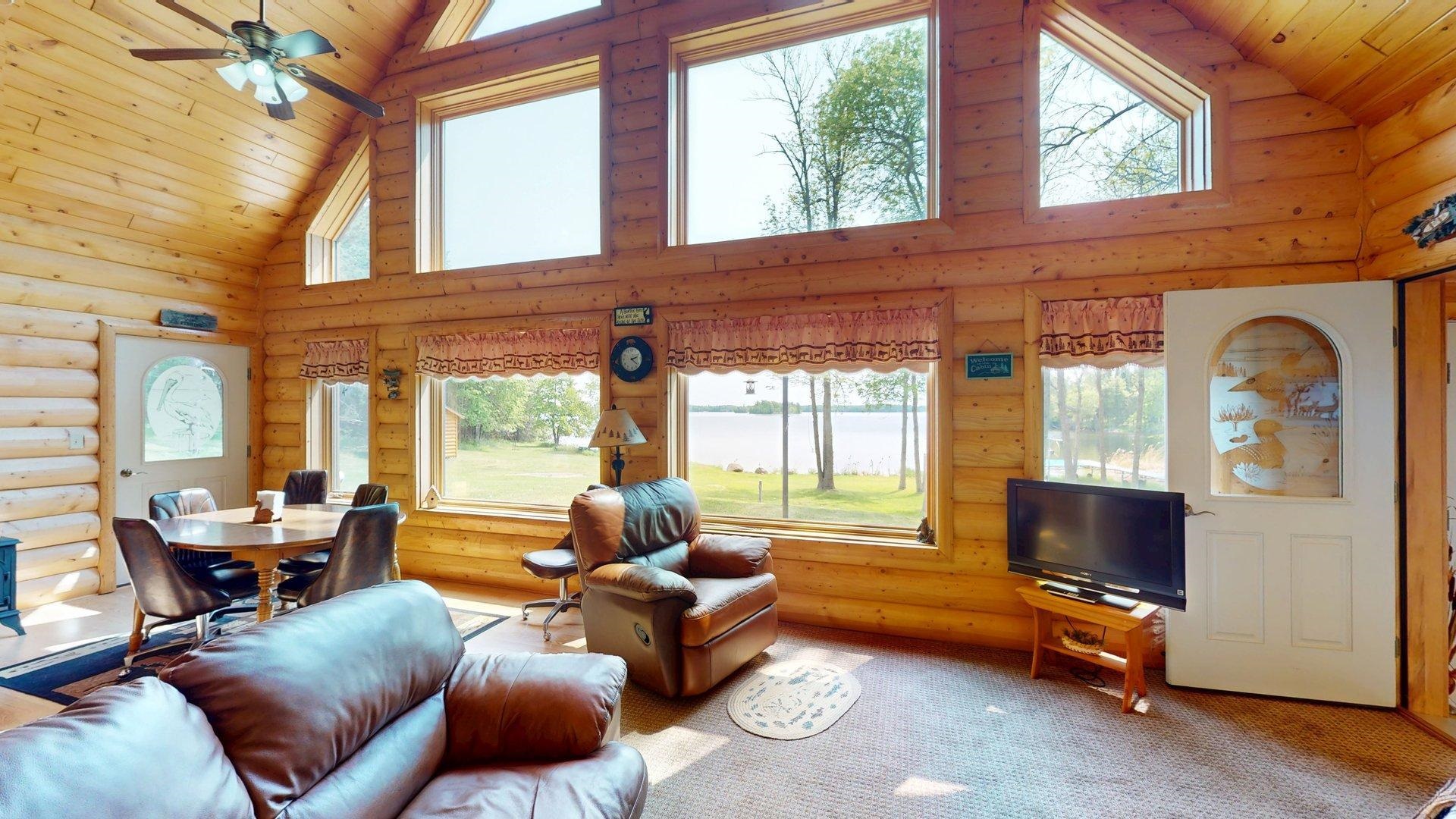 10898 Bessette Road Orr, MN 55771 - Photo 17 of 49 Living room featuring high vaulted ceiling, wooden ceiling, log walls, a ceiling fan, and light carpet