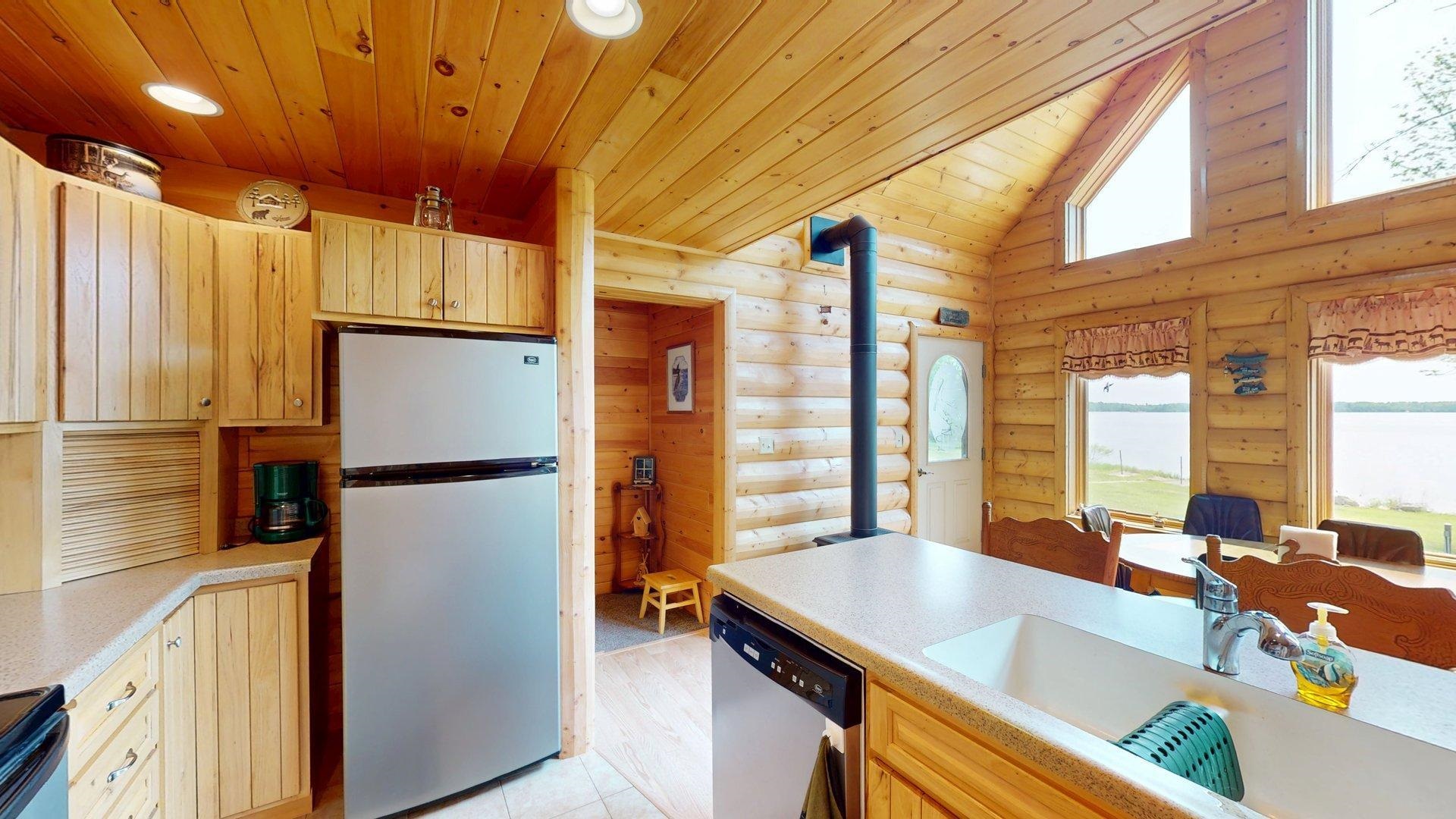 10898 Bessette Road Orr, MN 55771 - Photo 20 of 49 Kitchen with appliances with stainless steel finishes, wood ceiling, a sink, log walls, and light countertops