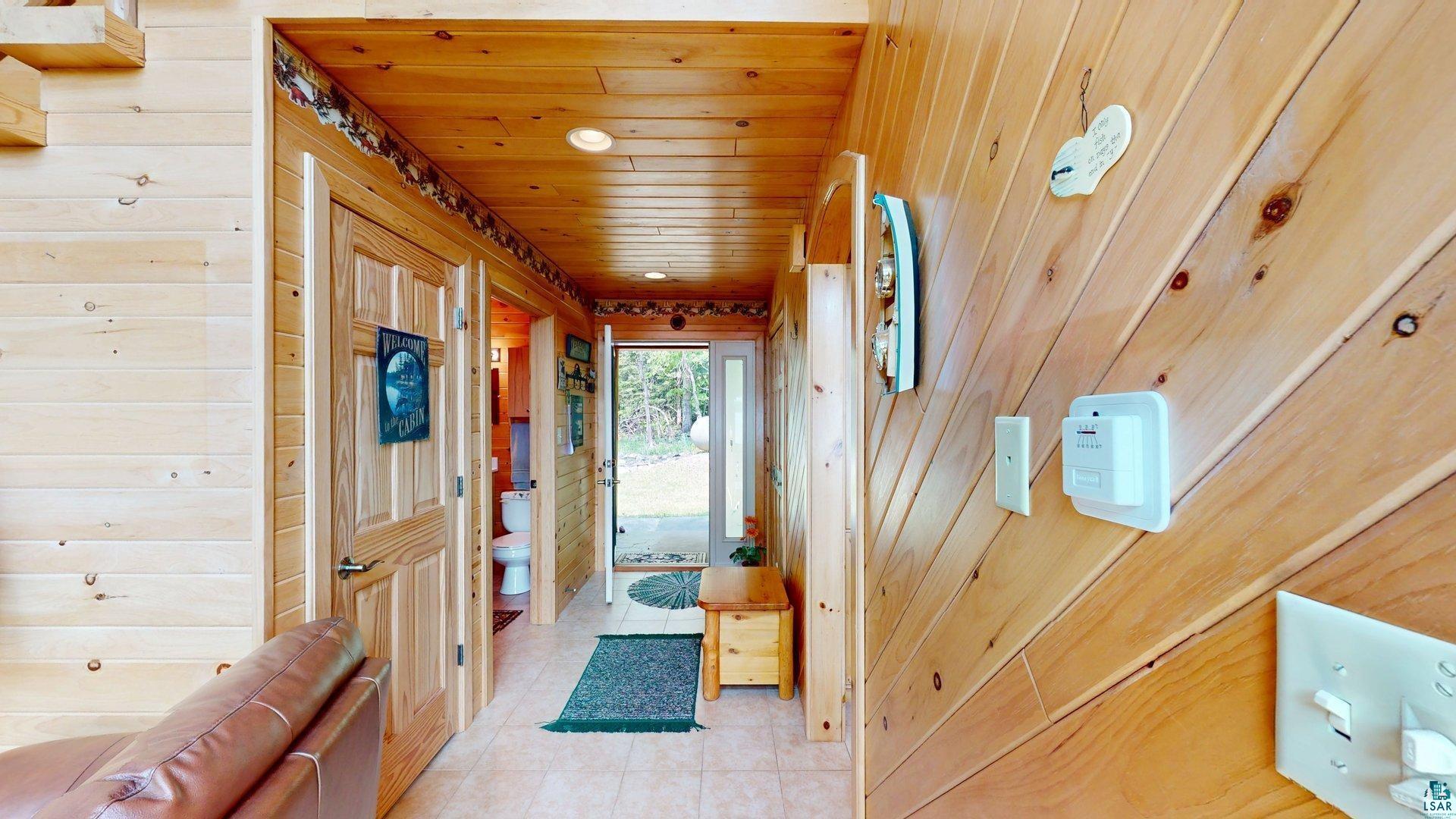 10898 Bessette Road Orr, MN 55771 - Photo 22 of 49 Hall with wood ceiling, wood walls, and light tile patterned flooring