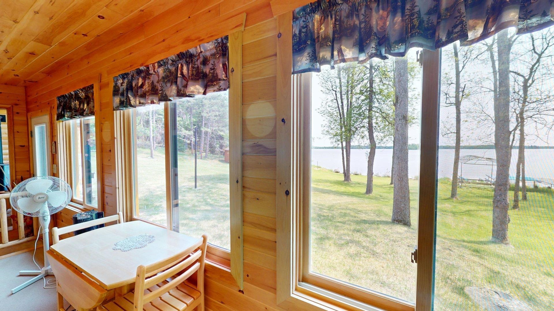 10898 Bessette Road Orr, MN 55771 - Photo 26 of 49 Sunroom featuring a water view, wooden walls, and wood finished floors