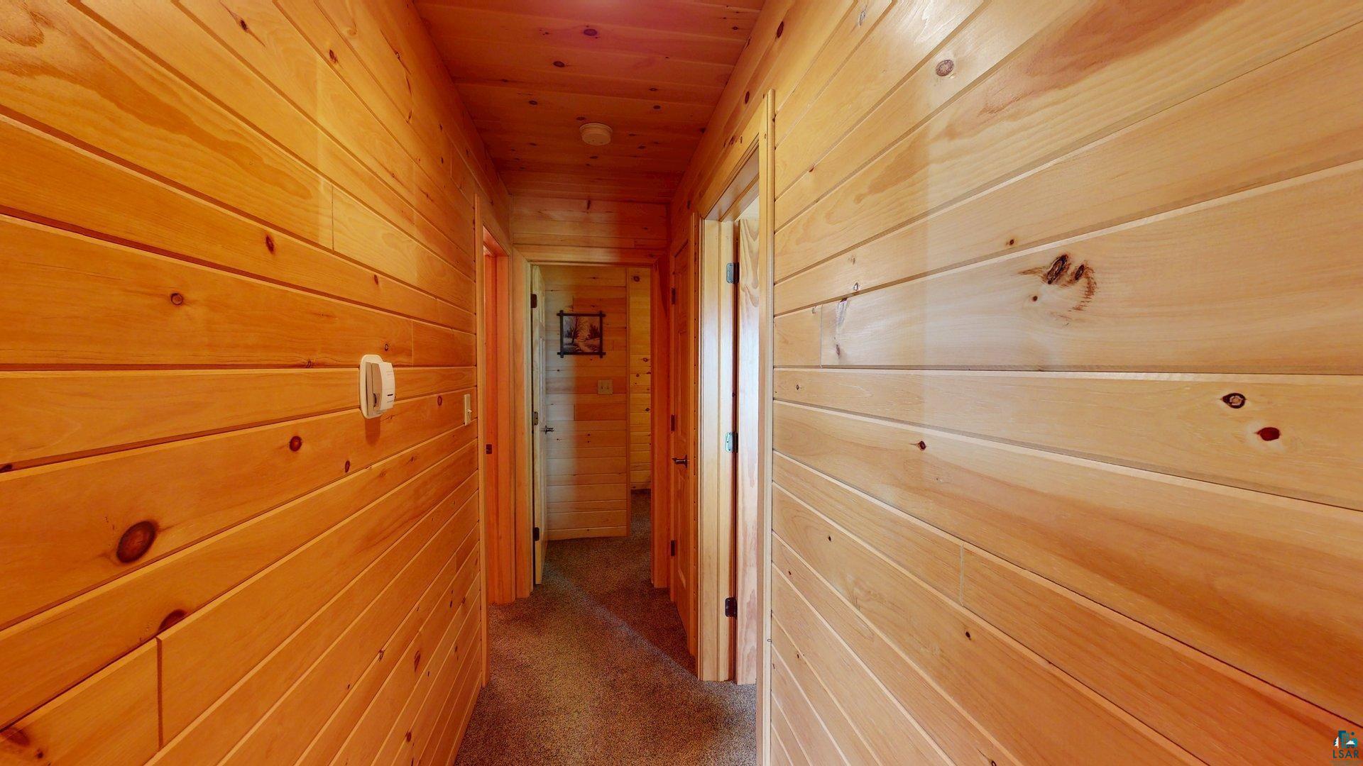 10898 Bessette Road Orr, MN 55771 - Photo 27 of 49 Hallway with wooden walls, wooden ceiling, and carpet