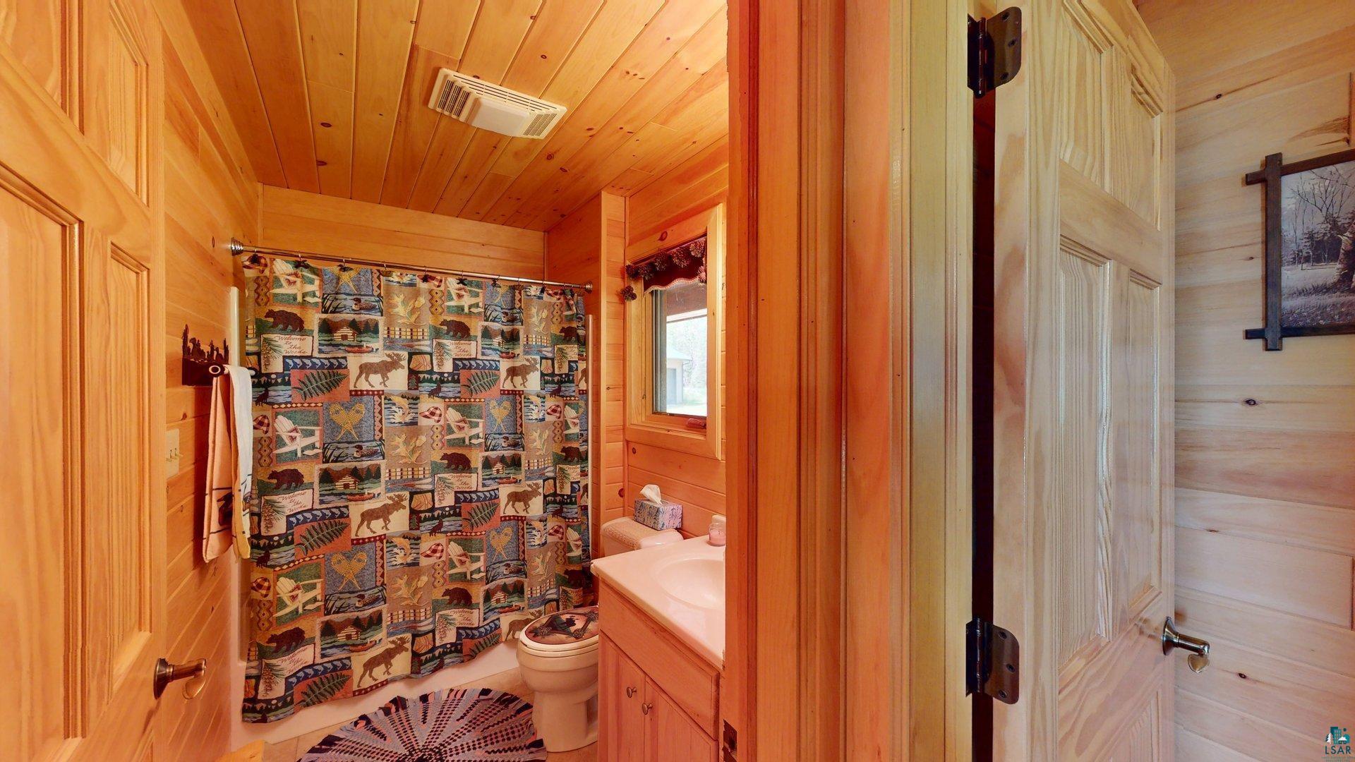 10898 Bessette Road Orr, MN 55771 - Photo 30 of 49 Full bath with wooden walls, vanity, toilet, wood ceiling, and a shower with shower curtain