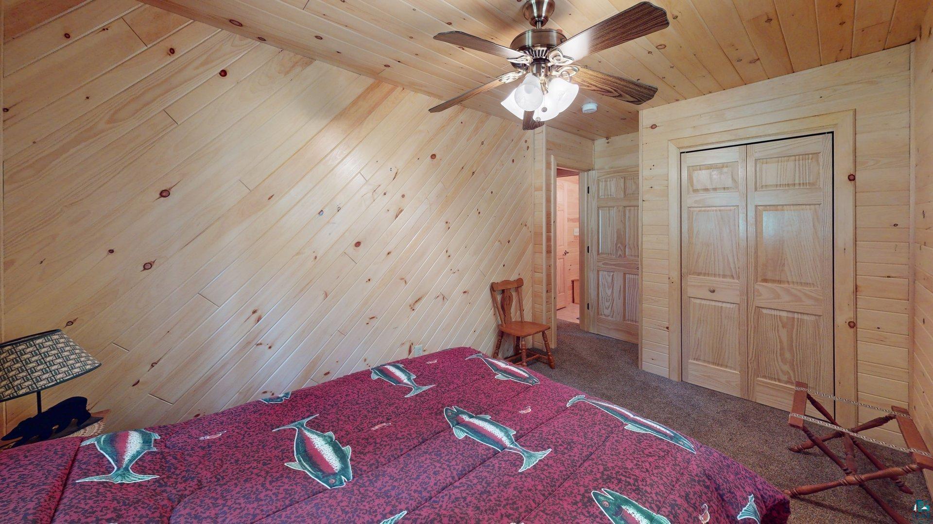 10898 Bessette Road Orr, MN 55771 - Photo 32 of 49 Unfurnished bedroom featuring wooden walls, wood ceiling, carpet, a ceiling fan, and a closet