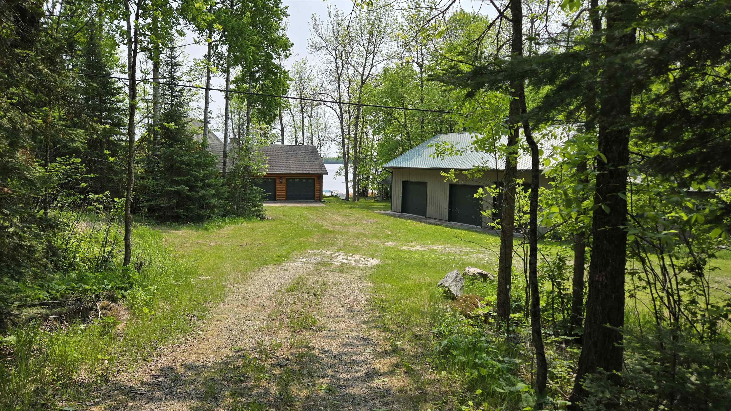 10898 Bessette Road Orr, MN 55771 - Photo 44 of 49 View of green lawn with a detached garage, driveway, and an outbuilding
