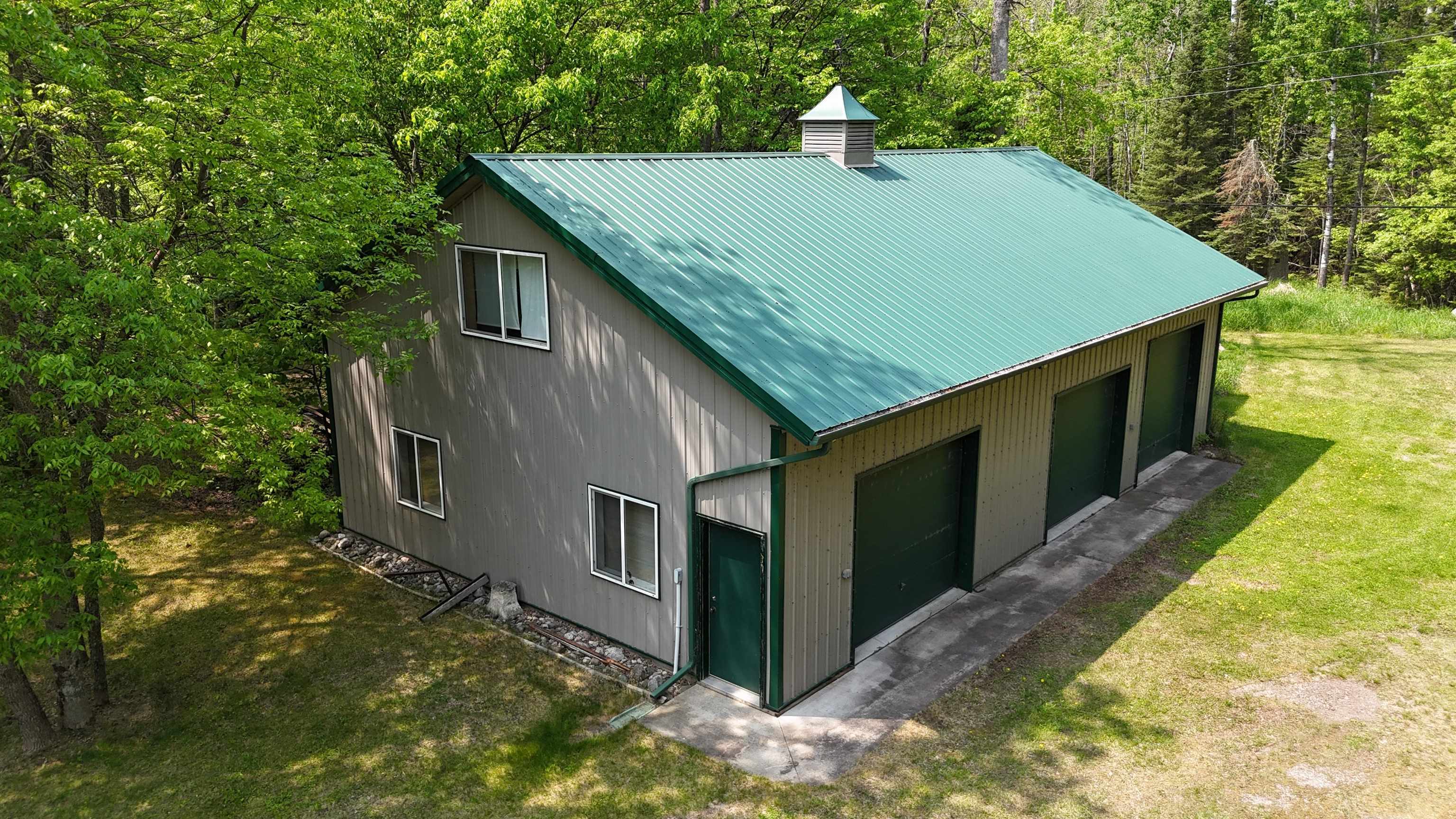 10898 Bessette Road Orr, MN 55771 - Photo 8 of 49 View of property exterior featuring a chimney, a yard, metal roof, and a wooded view