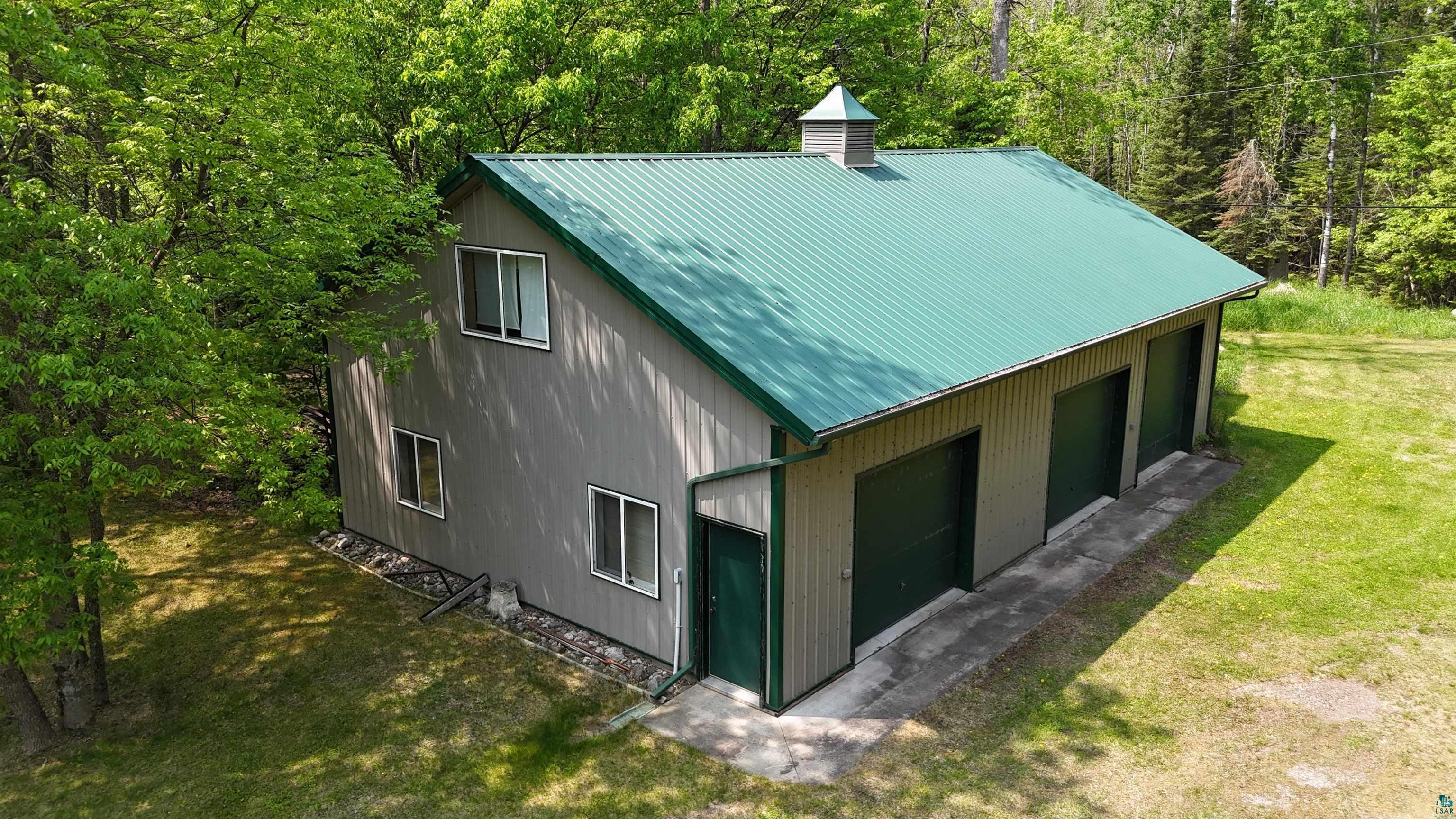10898 Bessette Road Orr, MN 55771 - Photo 8 of 49 View of property exterior featuring a chimney, a yard, metal roof, and a wooded view