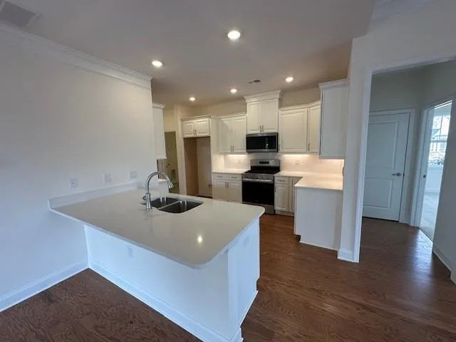 a kitchen with granite countertop white cabinets and black stainless steel appliances