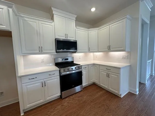 a kitchen with granite countertop white cabinets and white appliances