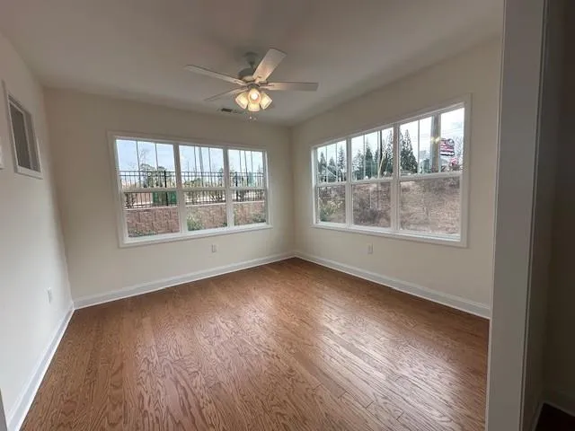 an empty room with wooden floor and windows