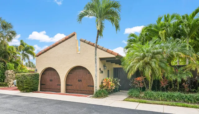 a view of a white house with a yard and palm trees