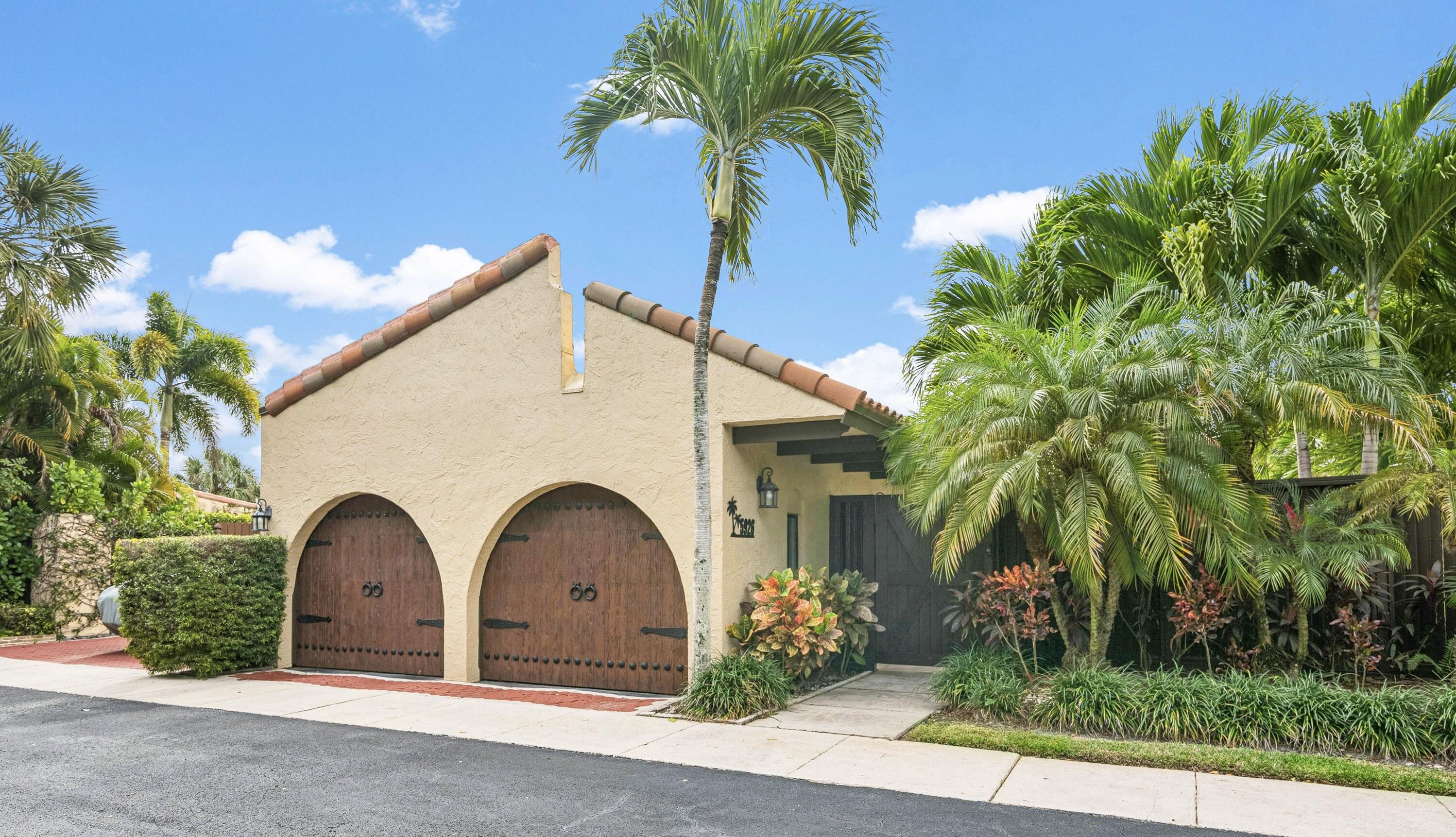 a view of a white house with a yard and palm trees