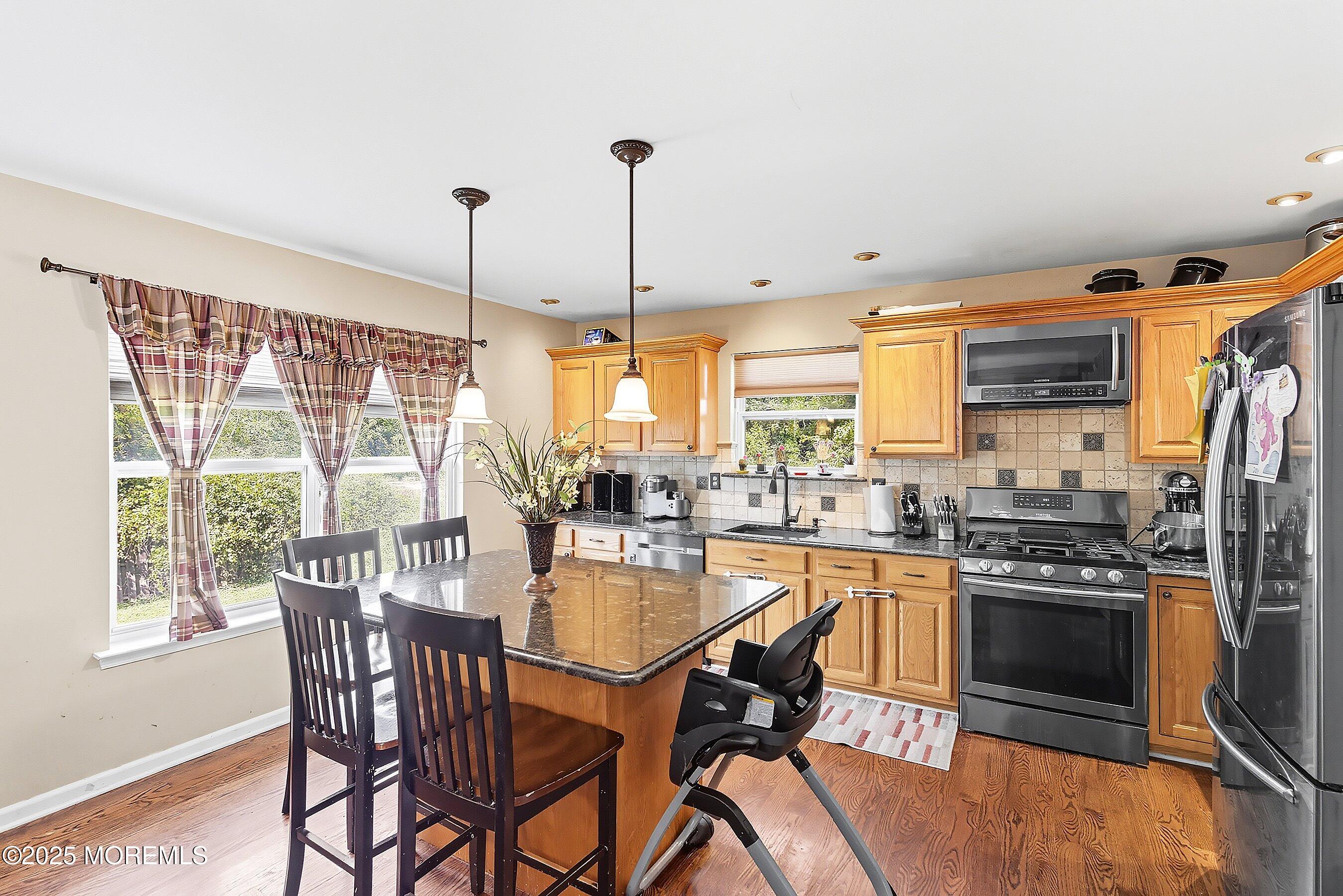 1090 Bennetts Mills Road Jackson, NJ 08527 - Photo 8 of 25 a kitchen with stainless steel appliances granite countertop a stove top oven a sink with a dining table and chairs