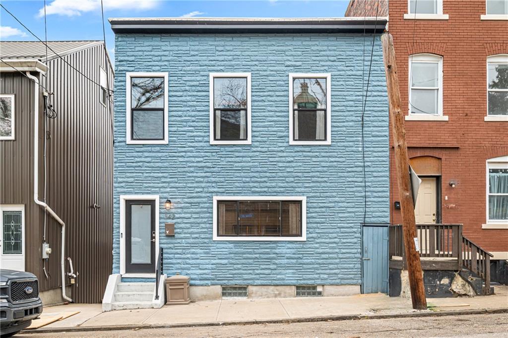 A saturated blue brick façade anchors the block — clean lines, modern windows, and a restrained, architectural presence.