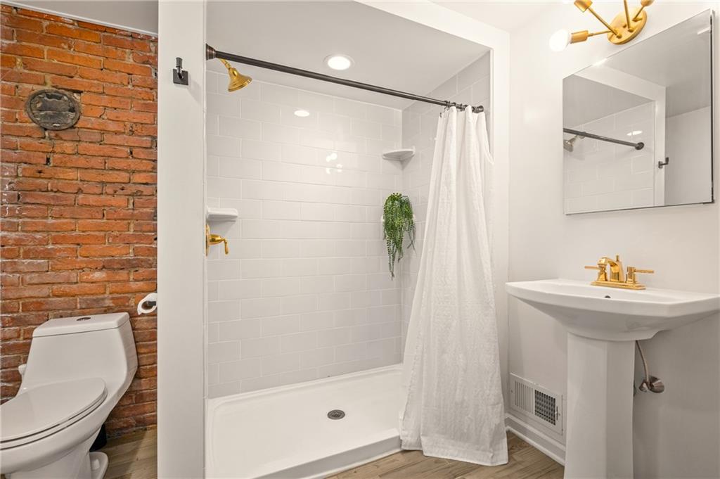 342 Harmar Street Pittsburgh, PA 15219 - Photo 23 of 30 Updated bath featuring subway tile surround, exposed brick accent, and warm brass fixtures for a subtle design contrast.