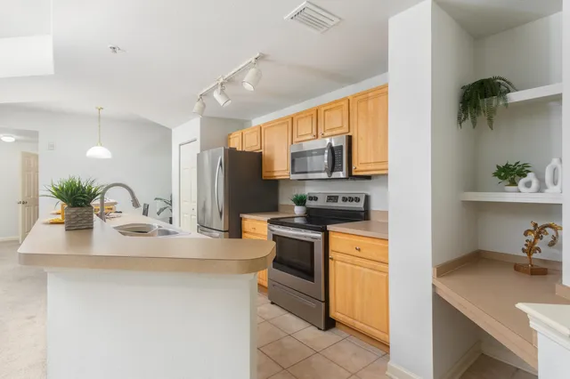 a kitchen with stainless steel appliances kitchen island granite countertop a sink a stove top oven a chimney and a center island