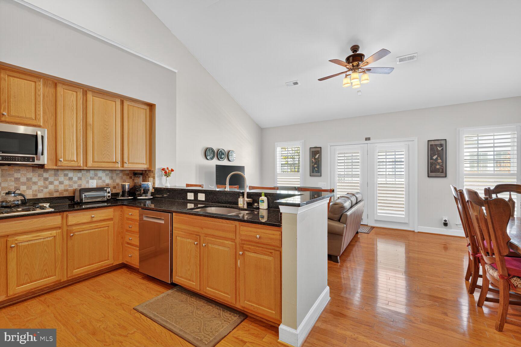 8912 Yellow Daisy Place Lorton, VA 22079 - Photo 3 of 24 a kitchen with stainless steel appliances granite countertop a sink dishwasher stove and wooden cabinets