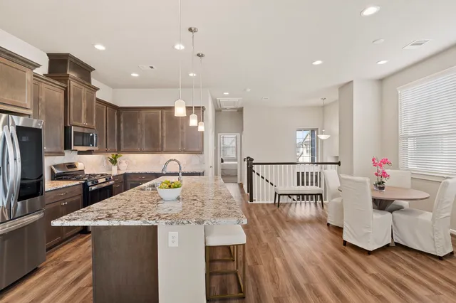 a kitchen with stainless steel appliances granite countertop a refrigerator a stove and a sink with wooden floor