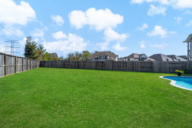 a view of yard with swimming pool and wooden fence