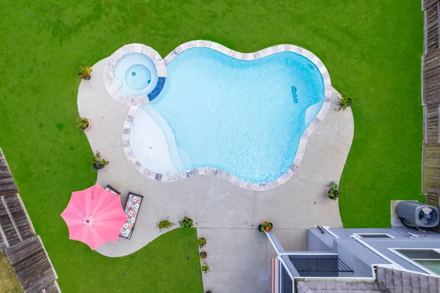 an aerial view of a swimming pool with outdoor space and seating area