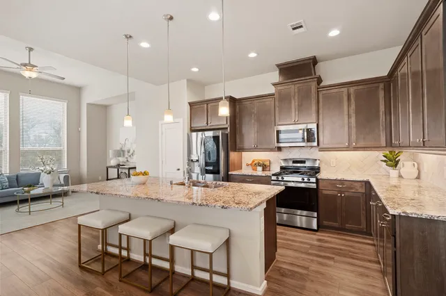 a kitchen with stainless steel appliances kitchen island granite countertop a sink stove and refrigerator