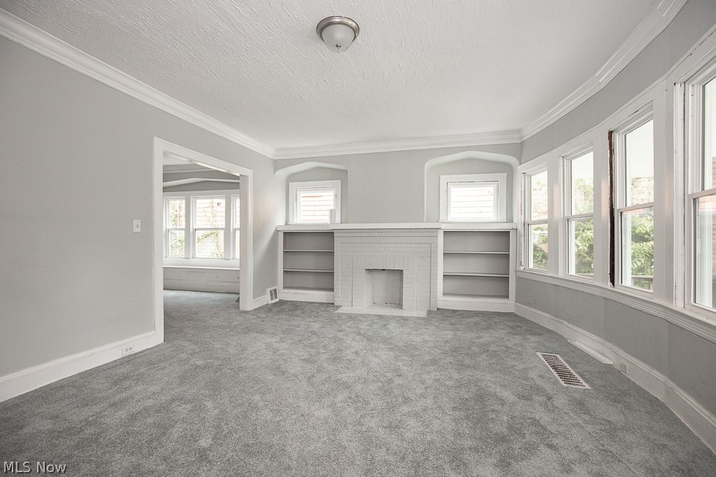 1000 Eddy Road Cleveland, OH 44108 - Photo 4 of 38 Unfurnished living room with ornamental molding, carpet floors, a textured ceiling, and a brick fireplace