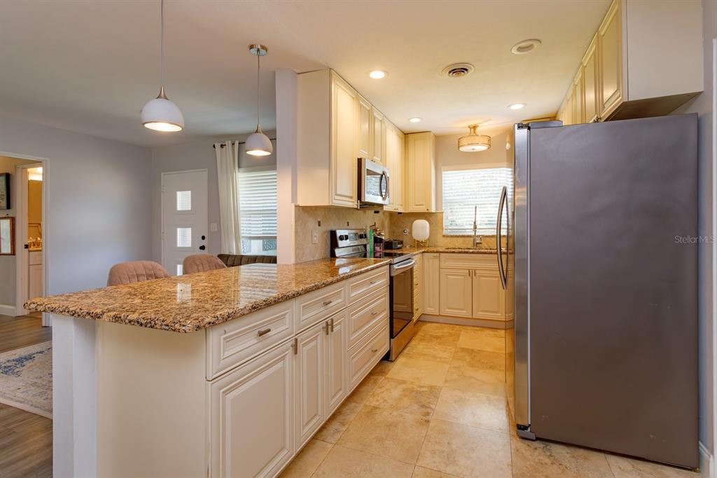 1105 Strathmore Drive Orlando, FL 32806 - Photo 11 of 25 a large kitchen with granite countertop a sink stainless steel appliances and cabinets