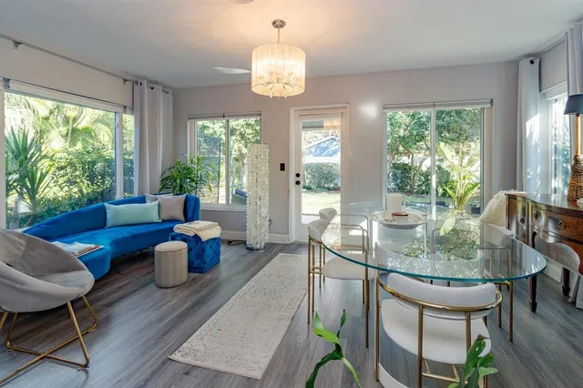 a dining room with wooden floor a chandelier a glass table and chairs