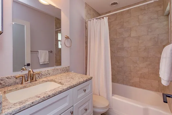 a bathroom with a granite countertop sink a toilet and bathtub