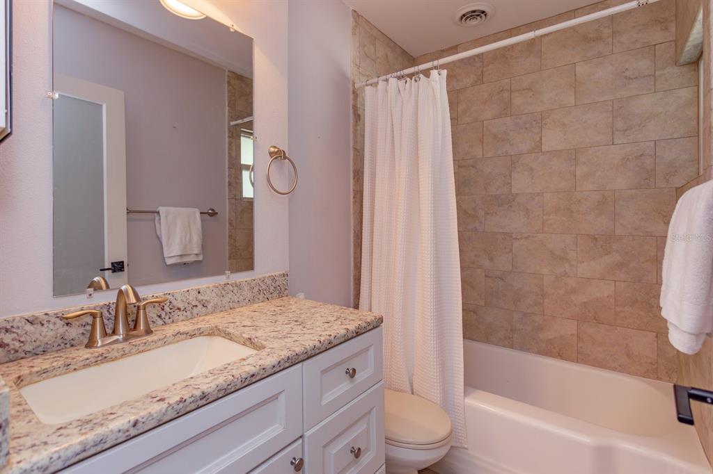 1105 Strathmore Drive Orlando, FL 32806 - Photo 19 of 25 a bathroom with a granite countertop sink a toilet and bathtub