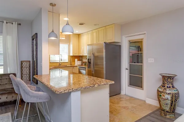 a kitchen with stainless steel appliances granite countertop a refrigerator a stove and a dining table with wooden floor