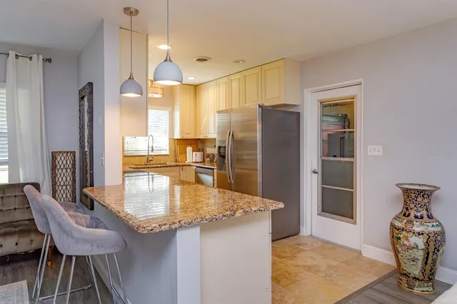 a kitchen with stainless steel appliances granite countertop a refrigerator a stove and a dining table with wooden floor