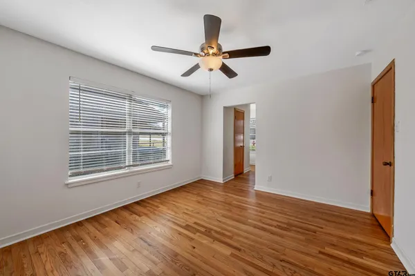 a view of an empty room with wooden floor and a window