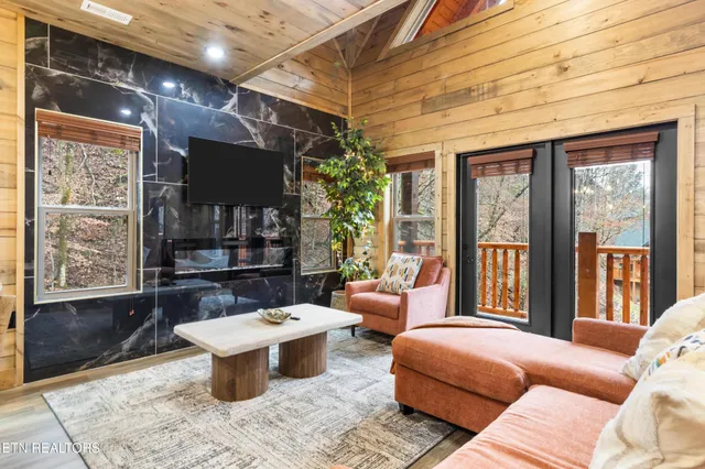 a living room with furniture a flat screen tv and kitchen view