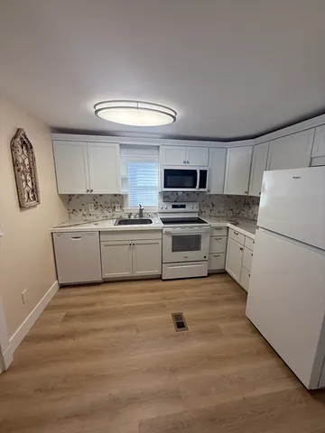 a kitchen with white cabinets and white appliances