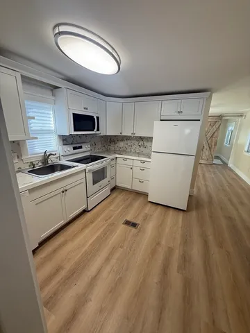 a kitchen with a sink a stove top oven and cabinetry