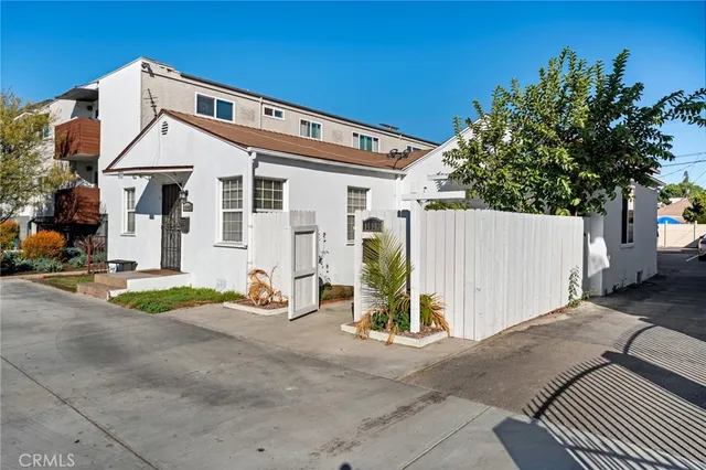 a view of a white house with many windows and plants