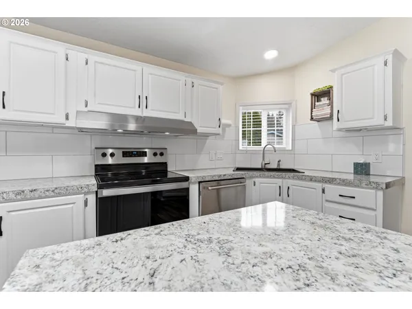 a kitchen with granite countertop a stove sink and cabinets