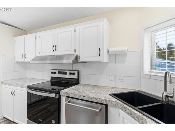 a kitchen with granite countertop white cabinets and a stove