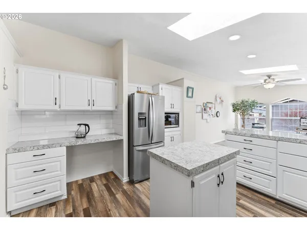 a kitchen with a refrigerator and countertop white cabinets