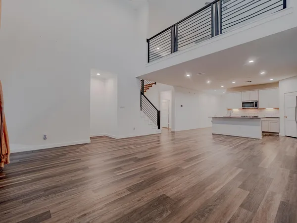 a view of kitchen and empty room with wooden floor