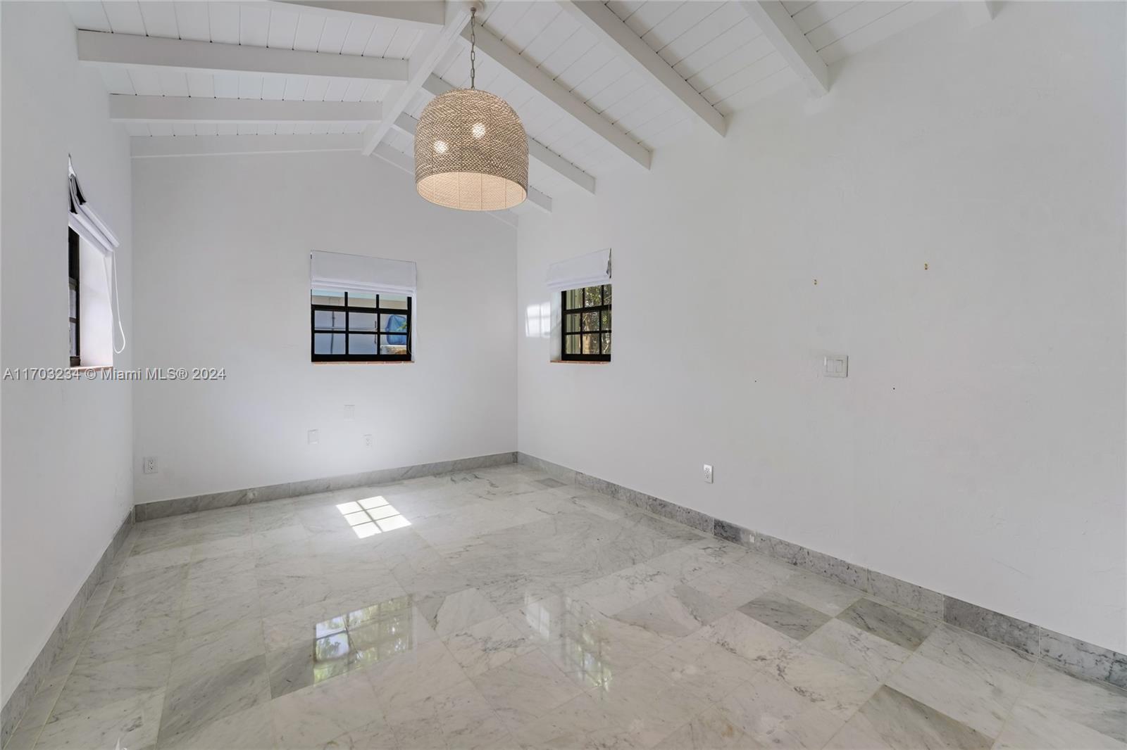 5660 Pine Tree Drive Miami Beach, FL 33140 - Photo 21 of 24 en empty room with windows and chandelier fan