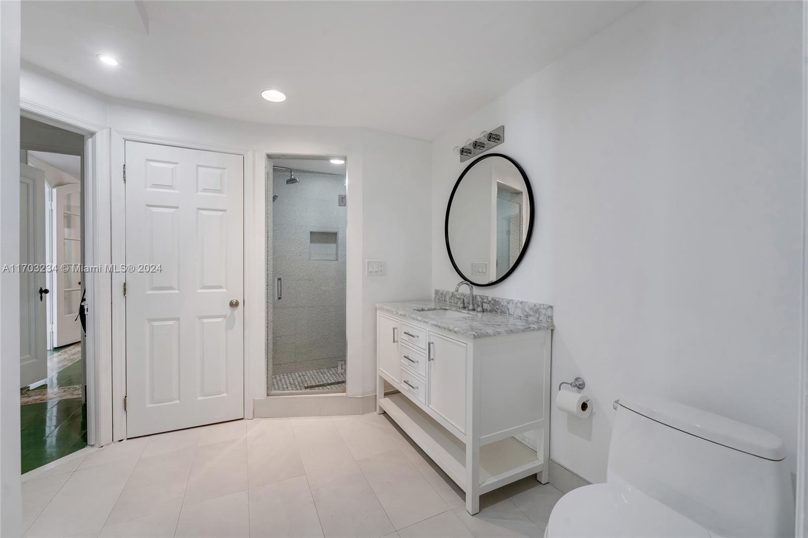 5660 Pine Tree Drive Miami Beach, FL 33140 - Photo 23 of 24 a spacious bathroom with a double vanity sink and a mirror