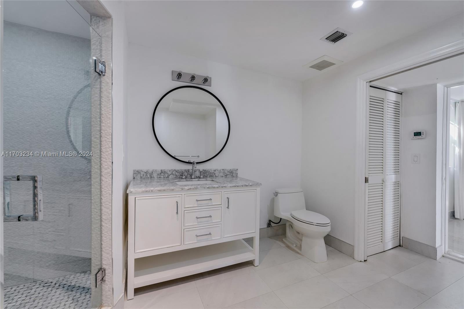 5660 Pine Tree Drive Miami Beach, FL 33140 - Photo 24 of 24 a bathroom with a granite countertop sink a toilet and a mirror