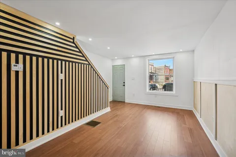 an entryway in a hall with wooden floor and a window